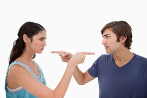 Couple pointing fingers at each other during a dispute, symbolizing premarital mistrust