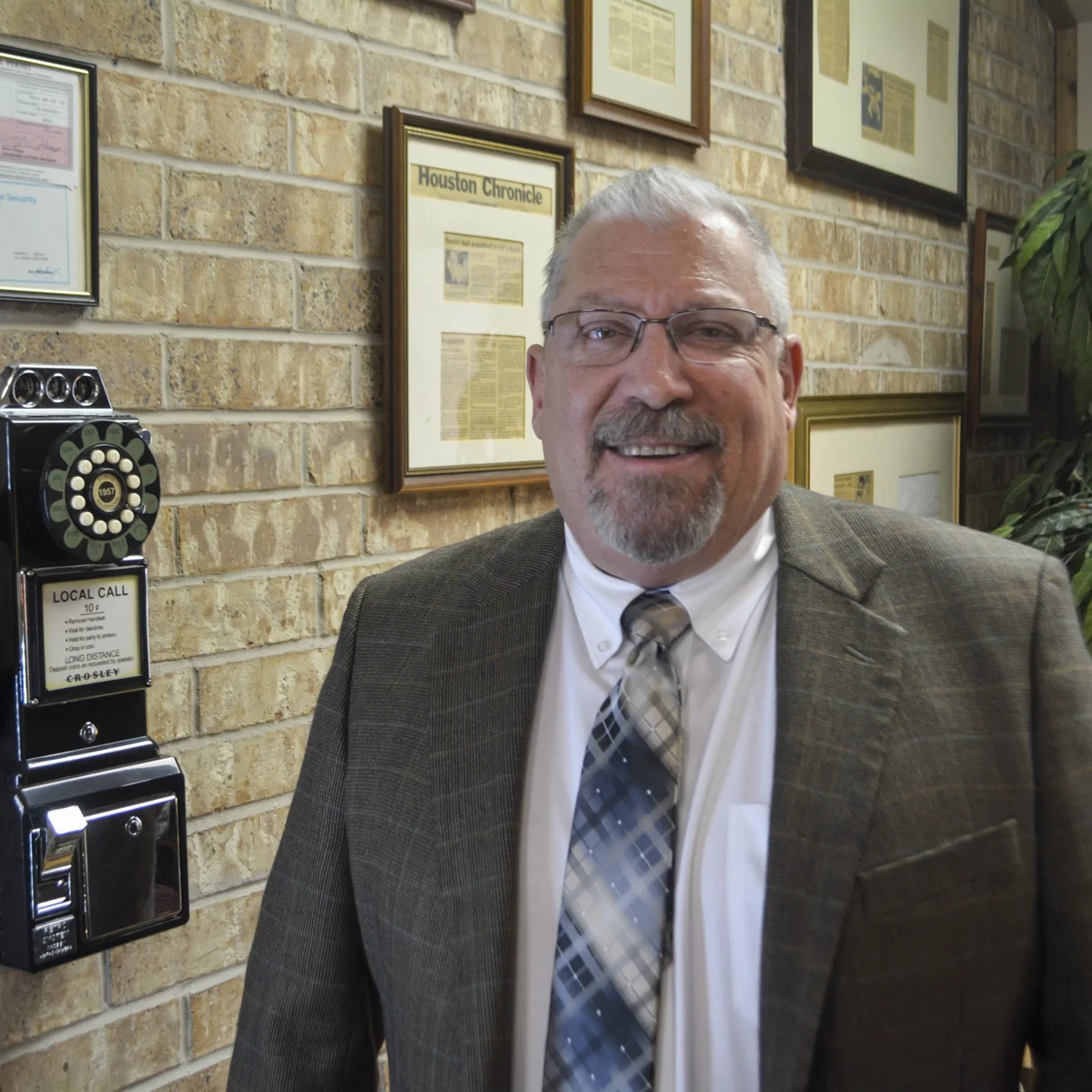 Keith Kucifer smiling in professional attire beside framed accolades and vintage office decor